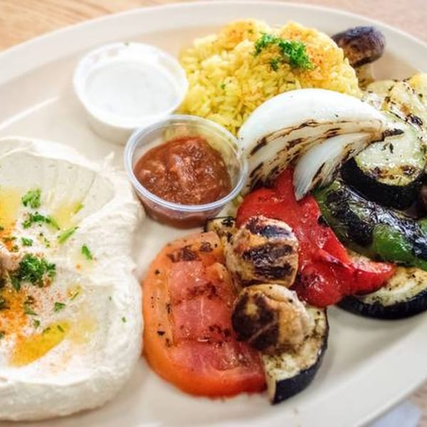 Mediterranean platter with hummus, yellow rice, grilled vegetables, and two dipping sauces.