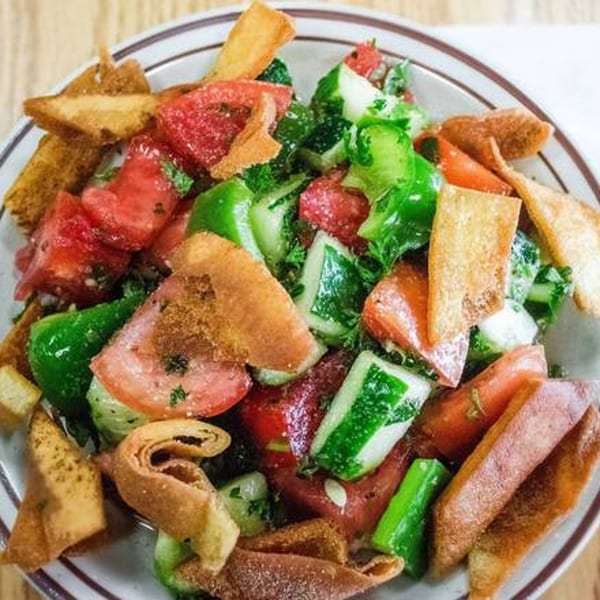 A vibrant Mediterranean fattoush salad with tomatoes, cucumbers, green peppers, and crispy pita bread.